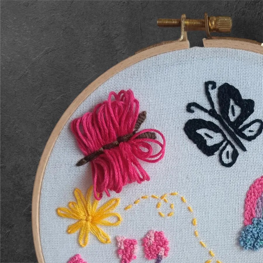 Tambour à broder representant la robe de mirabel dans Encanto, on peut voir deux papillons et une fleur jaune