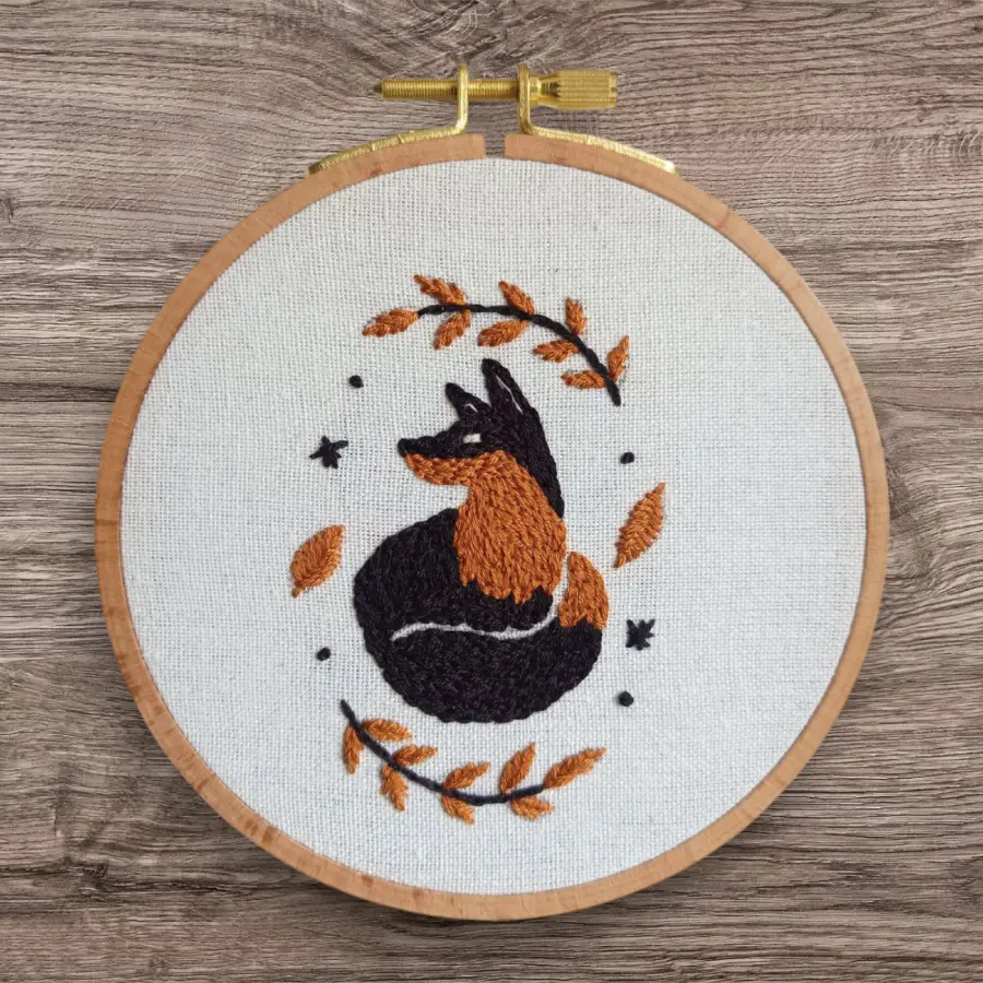 Renard brodé en orange et noir agrémenté de petites feuilles autour de lui