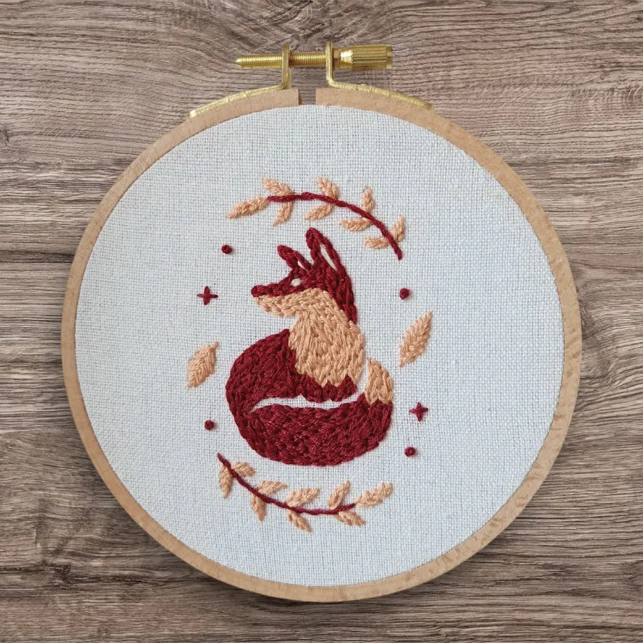 Broderie d'un Renard brodé en rouge framboise et beige agrémenté de petites feuilles autour de lui