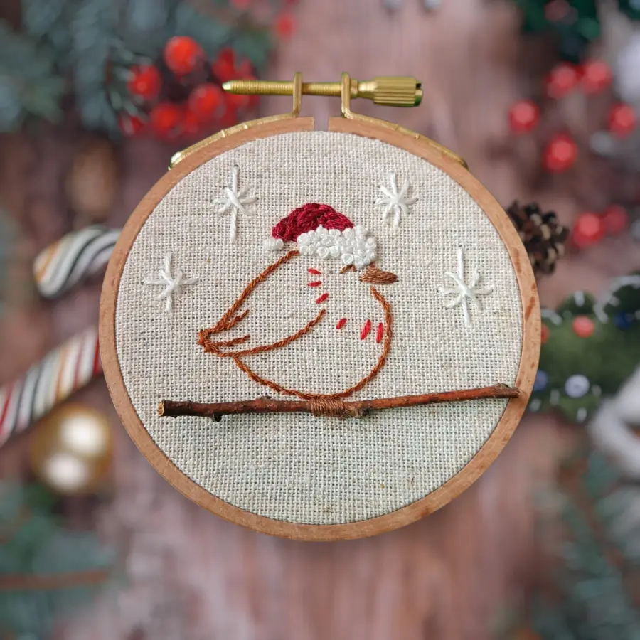 Décoration pour sapin de noël avec un petit rouge gorge portant un bonnet sur une veritable branche de bois